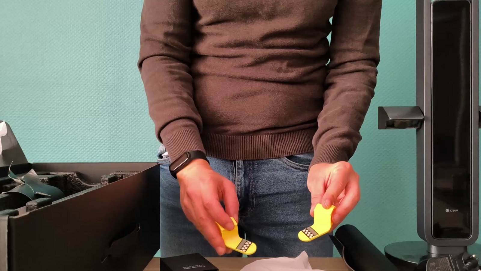 Déballage du CZUR Aura Pro : scanner, boîte ouverte et accessoires jaunes pour tenir les pages.